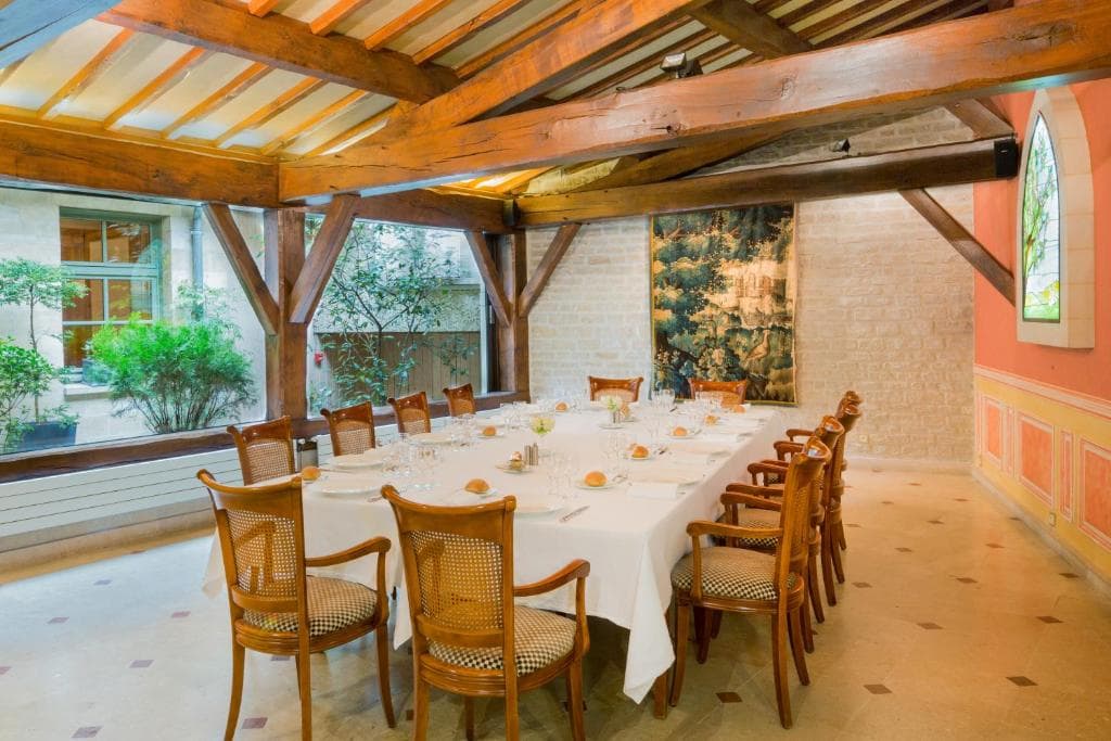 Salle de banquet avec poutres apparentes, tapisserie ancienne et vitraux
