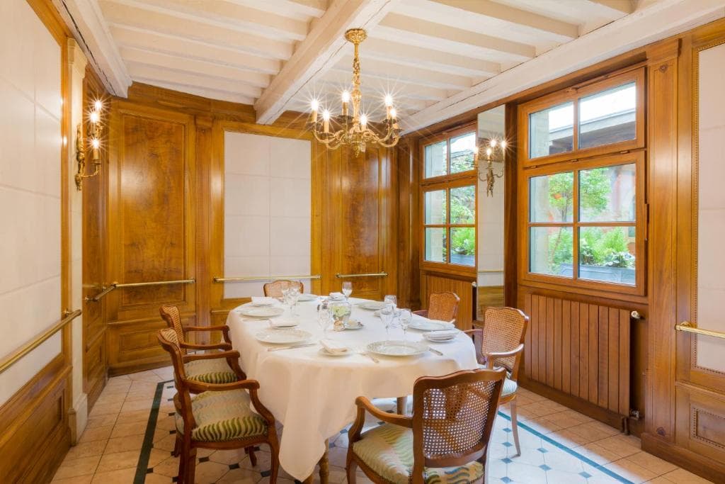 Salle intime avec boiseries, lustre en cristal et table ronde dressée
