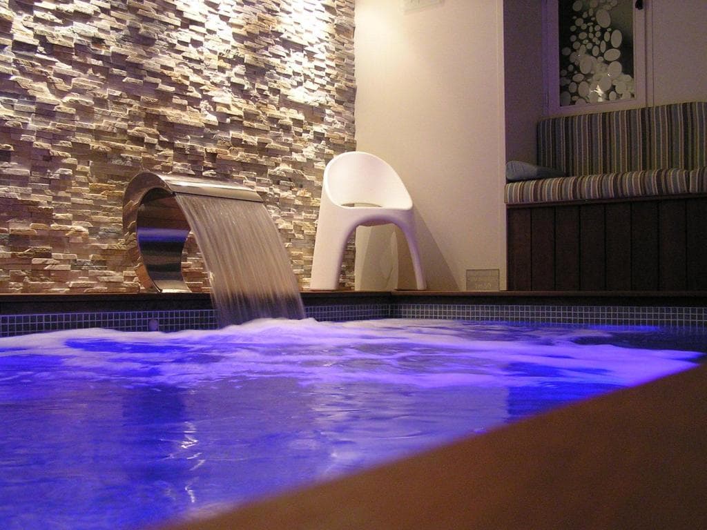 Spa du Prieuré illuminé la nuit avec cascade et éclairage bleu